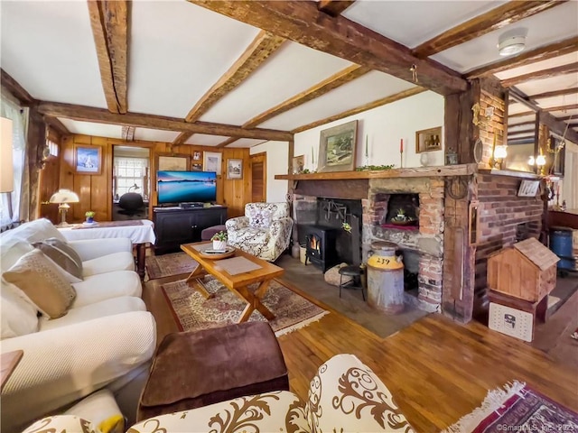 living room featuring beamed ceiling, hardwood / wood-style flooring, and a wood stove