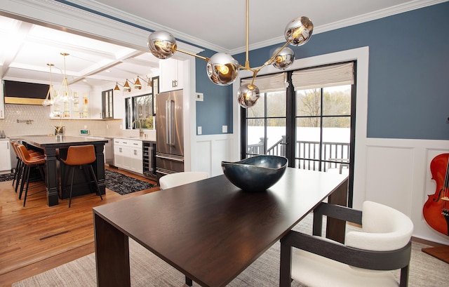 dining space featuring coffered ceiling, crown molding, wine cooler, light wood-type flooring, and beam ceiling