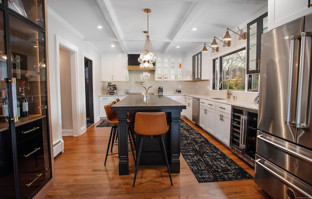 kitchen with stainless steel appliances, sink, beamed ceiling, a center island, and white cabinetry