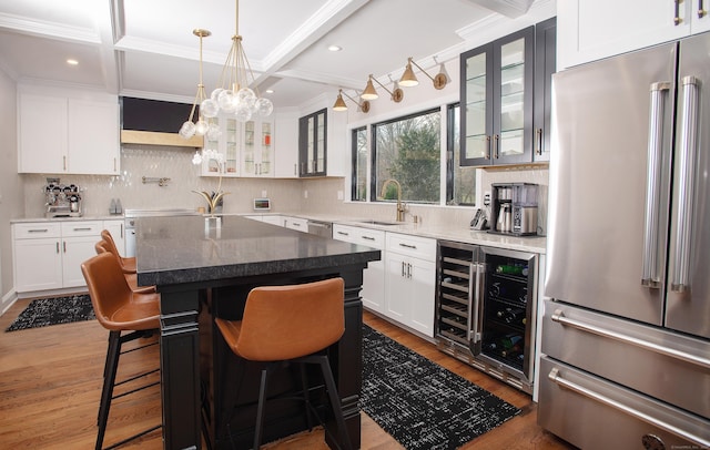 kitchen with a center island, sink, stainless steel appliances, dark stone counters, and white cabinets