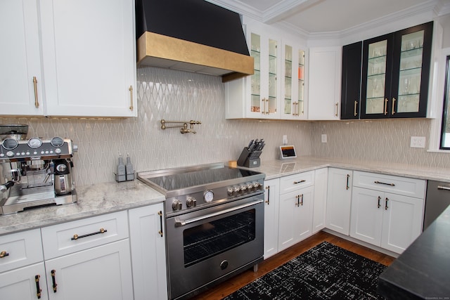 kitchen with high end stove, white cabinets, premium range hood, and ornamental molding