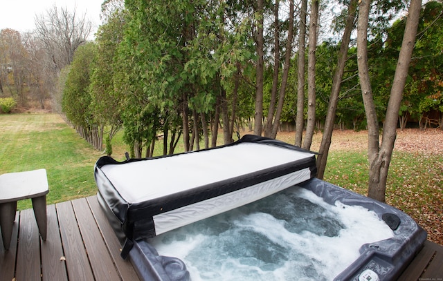 wooden terrace with a lawn and a covered hot tub