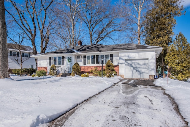 view of front facade featuring a garage, driveway, a chimney, and brick siding