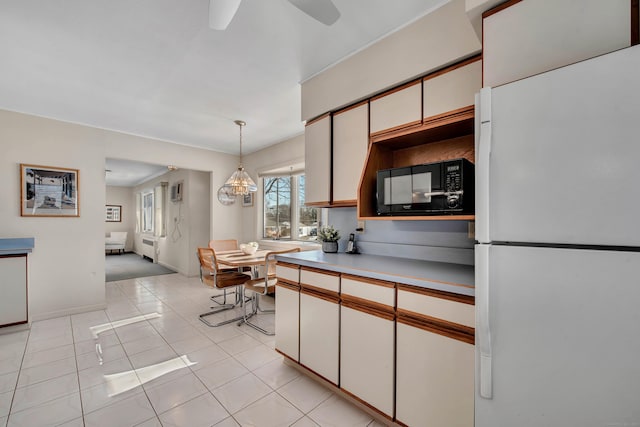 kitchen with decorative light fixtures, light countertops, freestanding refrigerator, white cabinetry, and black microwave