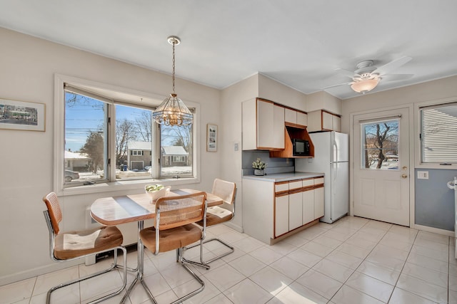 kitchen with baseboards, white cabinets, freestanding refrigerator, light countertops, and pendant lighting