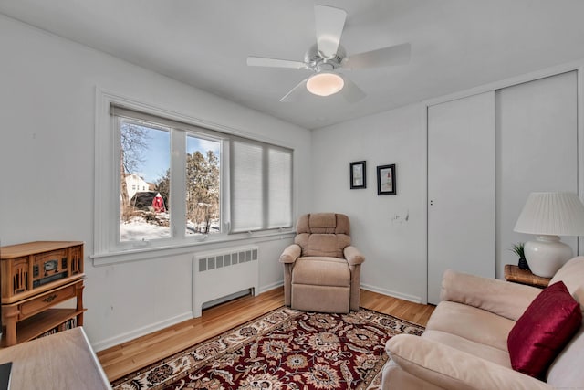 living room with a ceiling fan, light wood-style flooring, and radiator heating unit