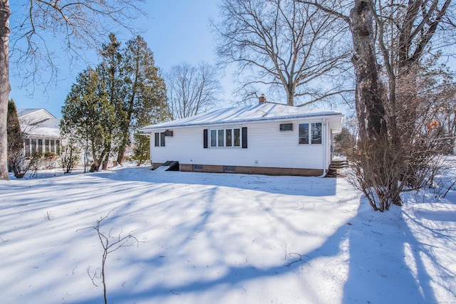 snow covered property with metal roof and a chimney