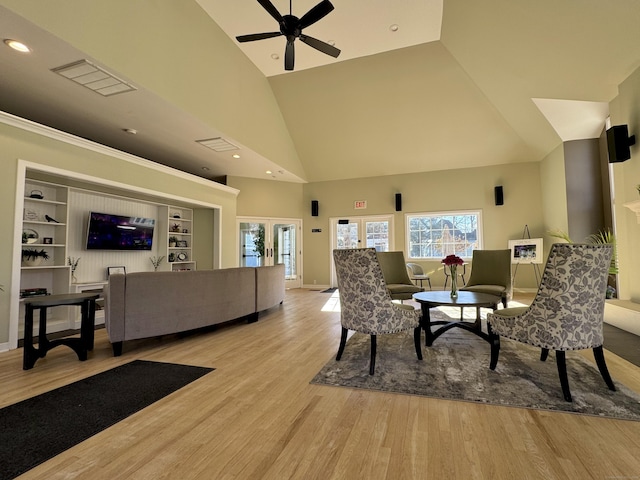 living room featuring french doors, built in shelves, ceiling fan, high vaulted ceiling, and light hardwood / wood-style flooring