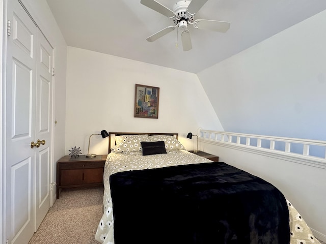 bedroom with ceiling fan, a closet, light carpet, and vaulted ceiling