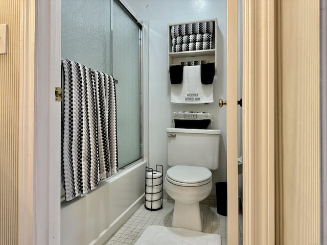 bathroom with tile patterned flooring, toilet, and combined bath / shower with glass door