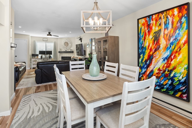 dining space featuring ceiling fan with notable chandelier and light wood-type flooring