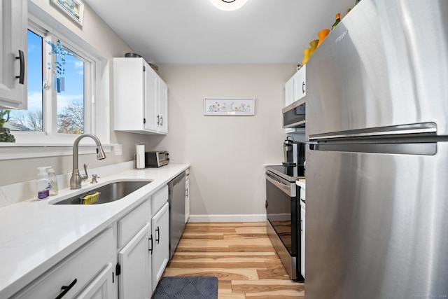 kitchen featuring white cabinets, appliances with stainless steel finishes, light hardwood / wood-style flooring, and sink