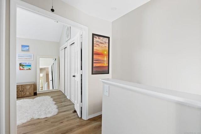 corridor featuring light hardwood / wood-style floors and lofted ceiling