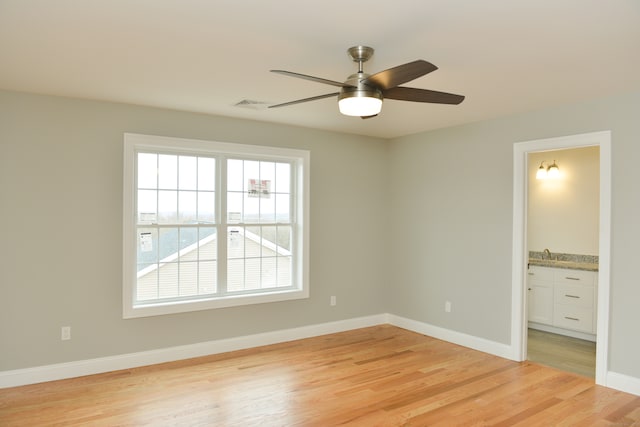 unfurnished bedroom featuring ceiling fan, light hardwood / wood-style floors, sink, and ensuite bathroom