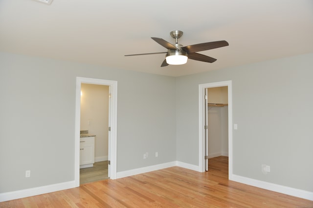 unfurnished bedroom featuring a walk in closet, ensuite bathroom, ceiling fan, light hardwood / wood-style floors, and a closet