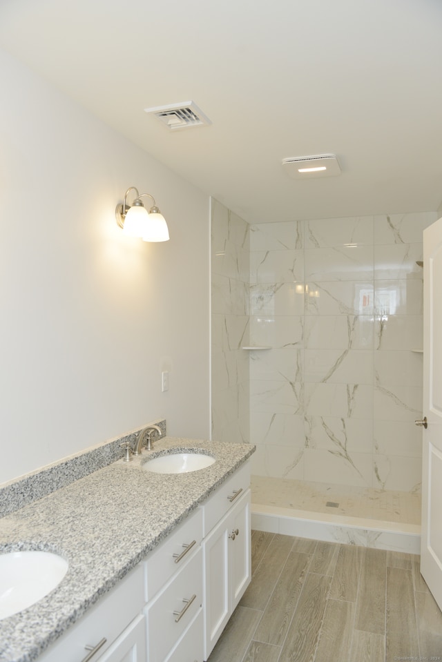 bathroom with a tile shower, vanity, and hardwood / wood-style flooring