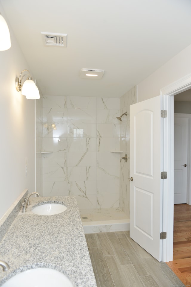 bathroom with tiled shower, vanity, and hardwood / wood-style flooring