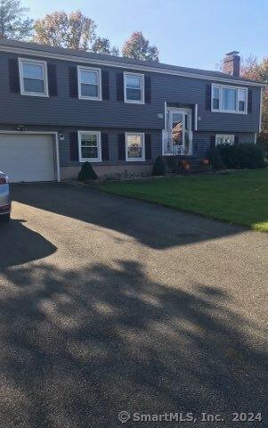 split foyer home with a garage and a front yard