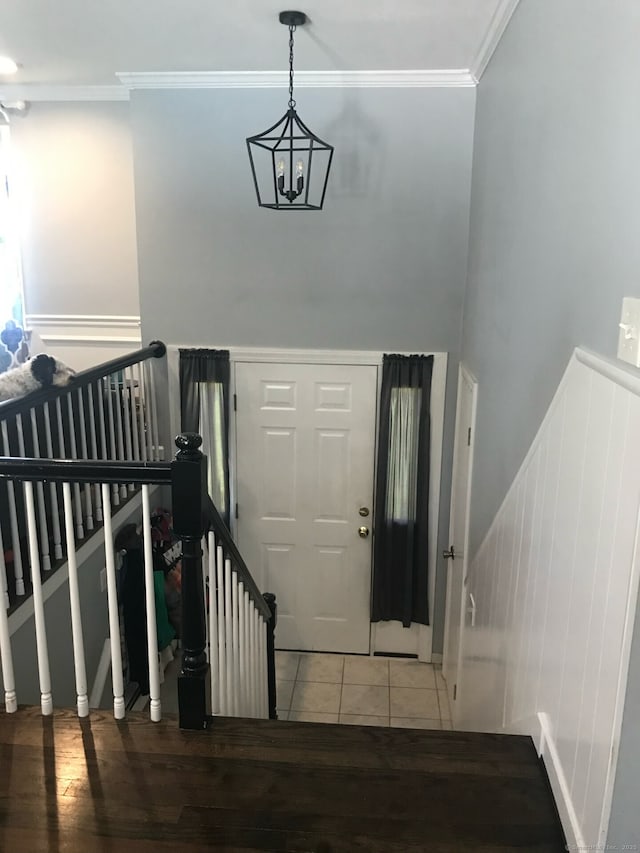 tiled entryway with a chandelier and crown molding