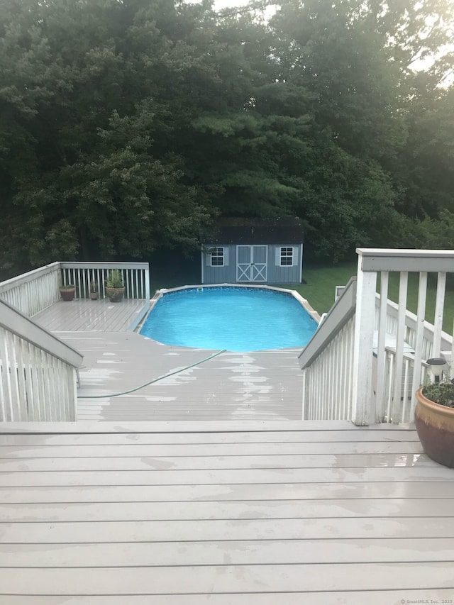 view of swimming pool with a shed and a wooden deck