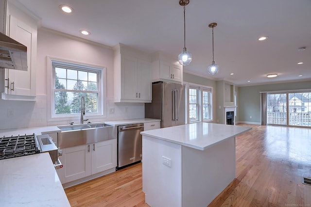 kitchen featuring stainless steel appliances, white cabinetry, sink, and wall chimney range hood