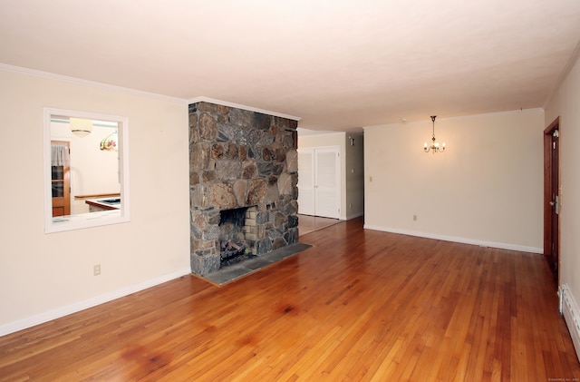 unfurnished living room featuring a baseboard heating unit, crown molding, an inviting chandelier, a fireplace, and hardwood / wood-style floors