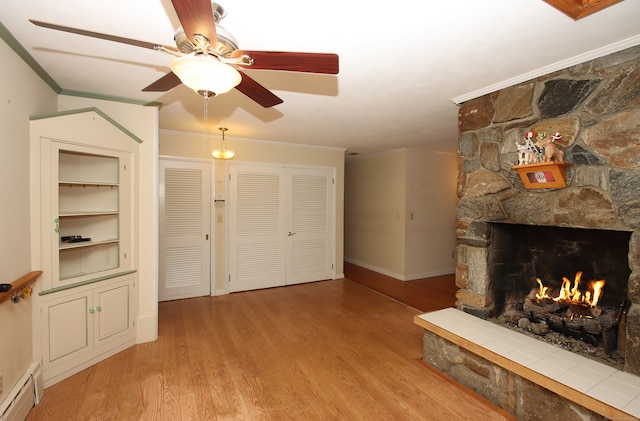 living room featuring a baseboard heating unit, crown molding, ceiling fan, a fireplace, and light hardwood / wood-style floors