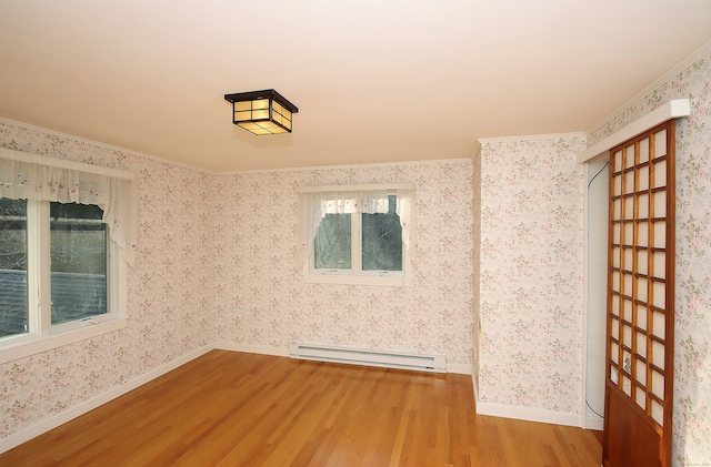 empty room with hardwood / wood-style floors, ornamental molding, and a baseboard heating unit