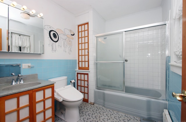 full bathroom featuring ornamental molding, a baseboard heating unit, shower / bath combination with glass door, tile walls, and toilet