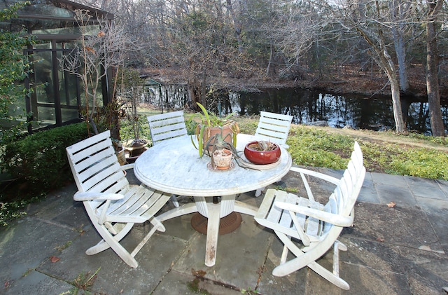 view of patio / terrace featuring a lanai and a water view