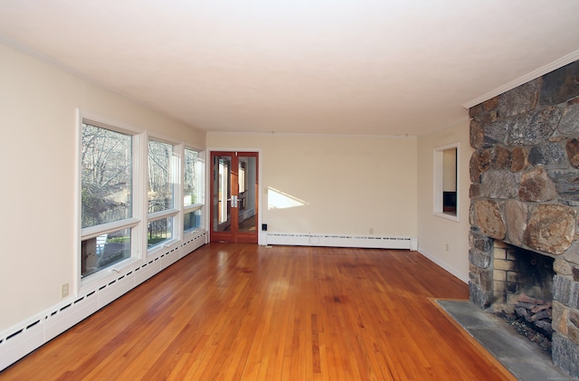 unfurnished living room with hardwood / wood-style flooring, a stone fireplace, and a baseboard radiator