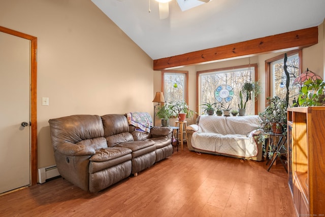 living room featuring ceiling fan, vaulted ceiling with skylight, wood-type flooring, and a baseboard heating unit