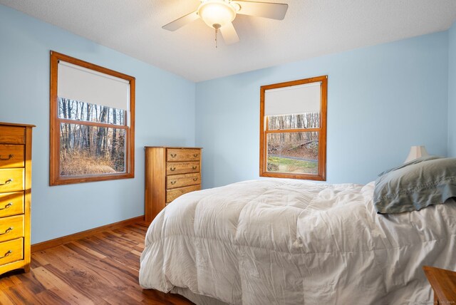 bedroom with a textured ceiling, ceiling fan, and dark wood-type flooring