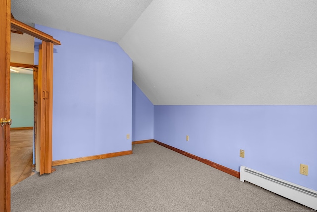 additional living space featuring vaulted ceiling, carpet, a textured ceiling, and a baseboard heating unit