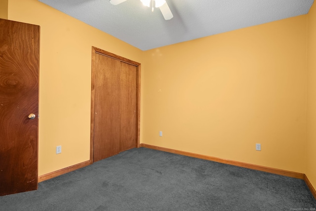 unfurnished bedroom with ceiling fan, dark carpet, a textured ceiling, and a closet