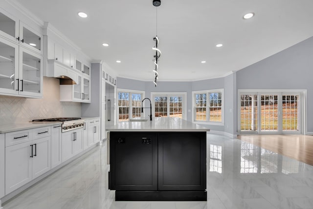 kitchen with stainless steel gas stovetop, plenty of natural light, white cabinets, and an island with sink