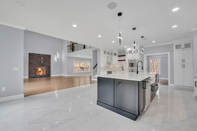 kitchen featuring white cabinetry, a wealth of natural light, crown molding, and an island with sink