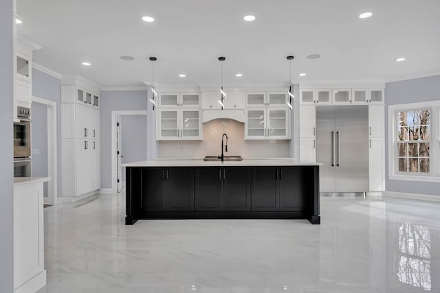 kitchen with stainless steel built in refrigerator, hanging light fixtures, crown molding, and an island with sink