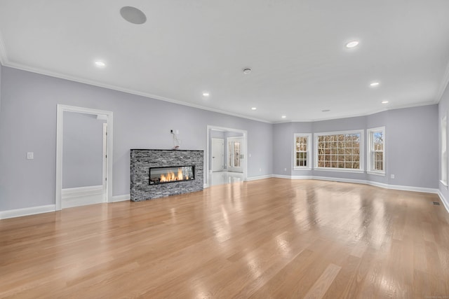 unfurnished living room featuring light hardwood / wood-style floors, a stone fireplace, and ornamental molding