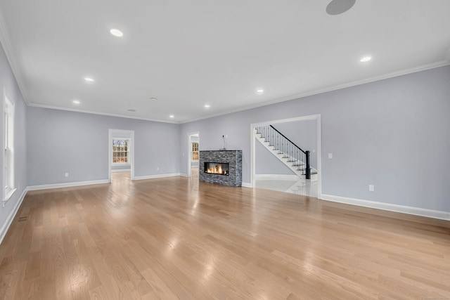 unfurnished living room featuring a stone fireplace, light wood-type flooring, and crown molding