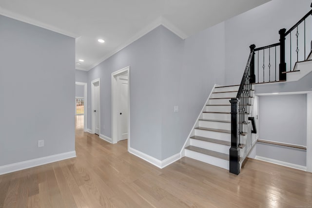 stairway with wood-type flooring and crown molding