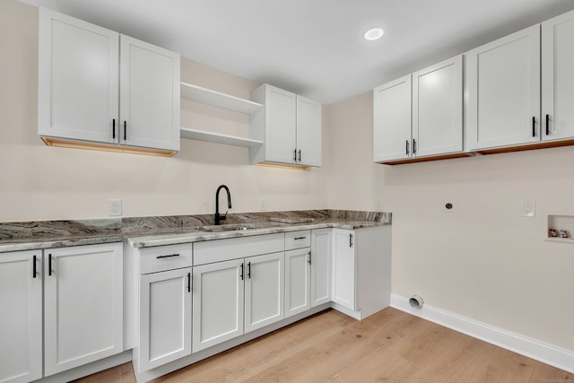 laundry room featuring hookup for an electric dryer, hookup for a washing machine, cabinets, sink, and light hardwood / wood-style floors