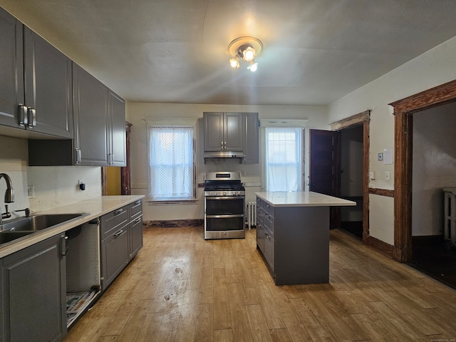 kitchen featuring sink, stainless steel range oven, light hardwood / wood-style floors, gray cabinets, and a kitchen island