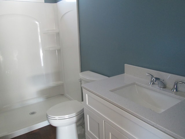 bathroom featuring toilet, vanity, and walk in shower