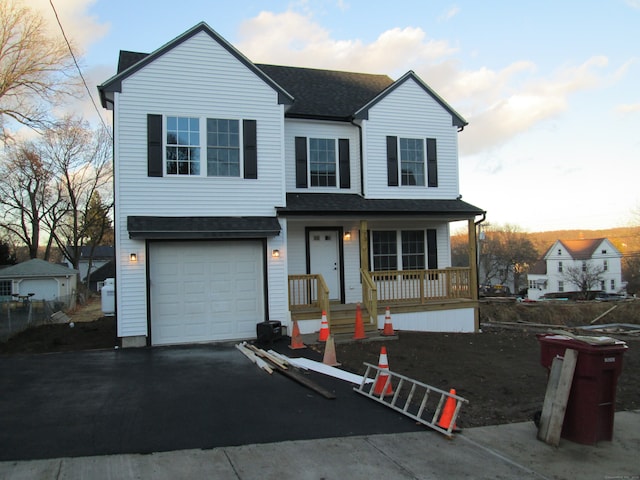 front facade featuring covered porch and a garage