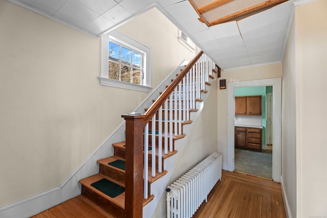 stairway featuring radiator, crown molding, and parquet flooring