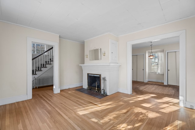 unfurnished living room featuring hardwood / wood-style flooring, radiator, and ornamental molding