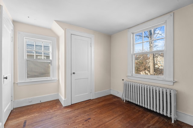 interior space with dark hardwood / wood-style flooring, a closet, and radiator heating unit