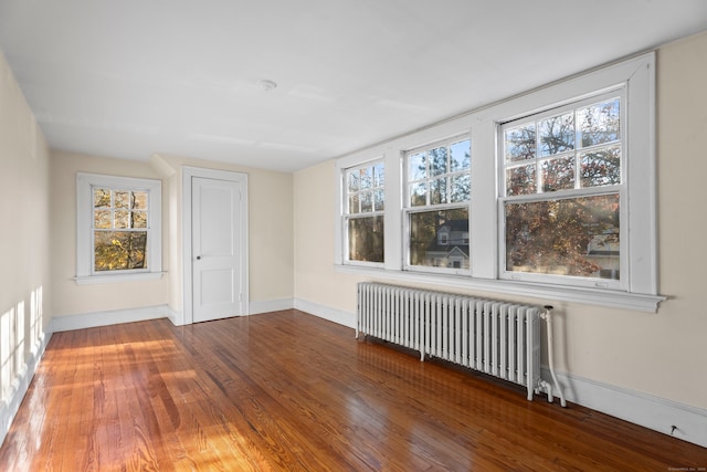 empty room with hardwood / wood-style floors and radiator