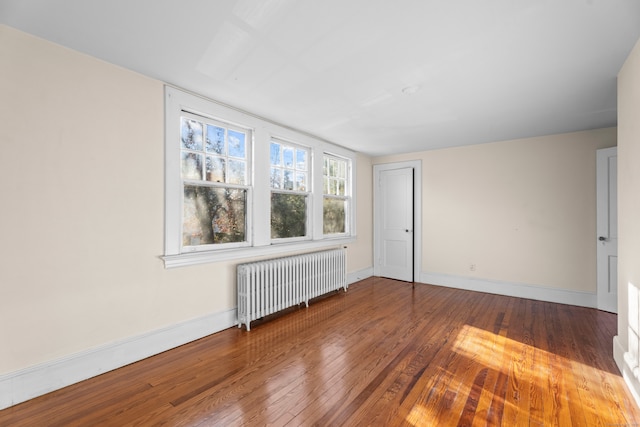 spare room with radiator heating unit and wood-type flooring